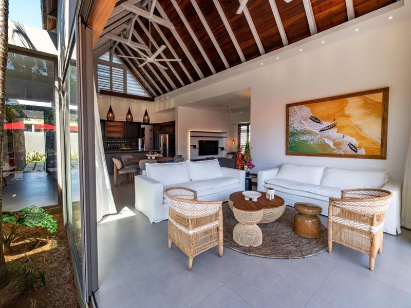 Spacious open-plan living area featuring a vaulted timber-beamed ceiling, large sliding glass doors, and a seamless transition to the kitchen and dining space.