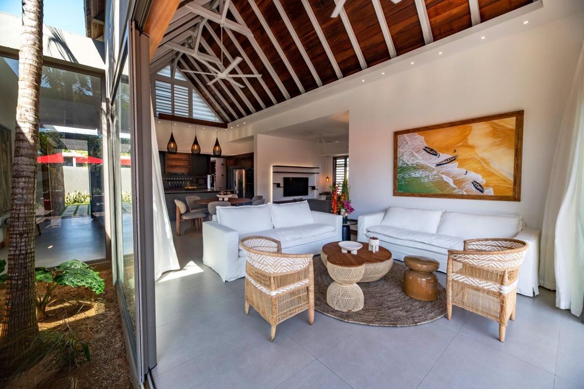 Spacious open-plan living area featuring a vaulted timber-beamed ceiling, large sliding glass doors, and a seamless transition to the kitchen and dining space.