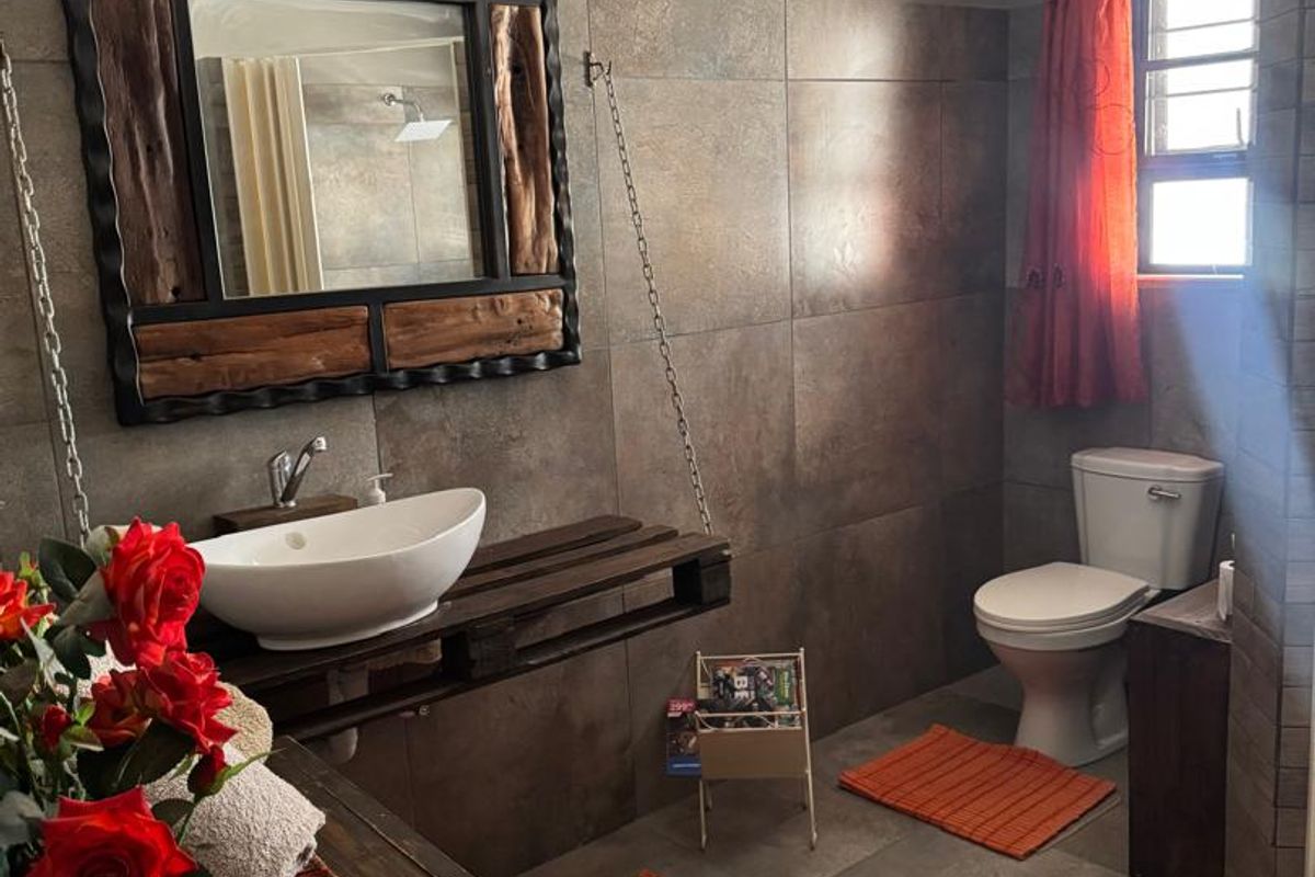 A modern bathroom featuring large format wall tiles, a vessel sink with wall-mounted faucet, and a standard ceramic toilet.