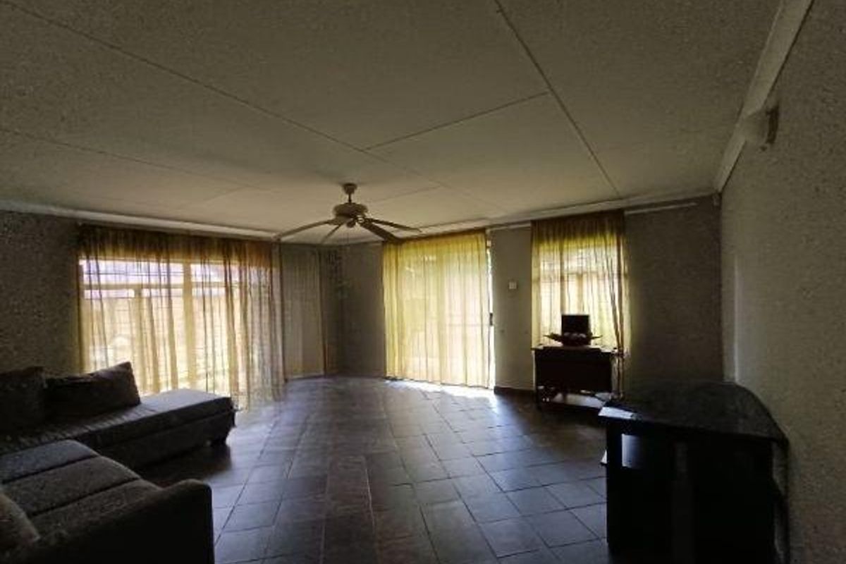 Spacious living area featuring tiled flooring, a ceiling fan, and large sliding glass doors providing ample natural light.