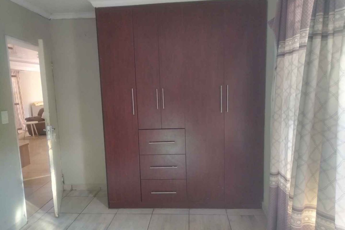 A bedroom featuring built-in dark wood cabinetry and tiled flooring, providing functional storage space.