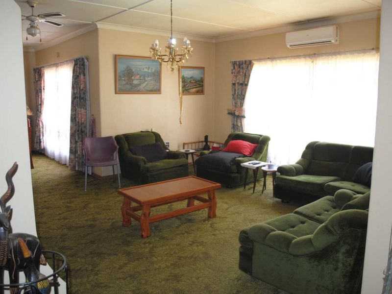 Spacious living room featuring carpet flooring, a ceiling fan, and a wall-mounted air conditioning unit, offering a comfortable and functional living space.