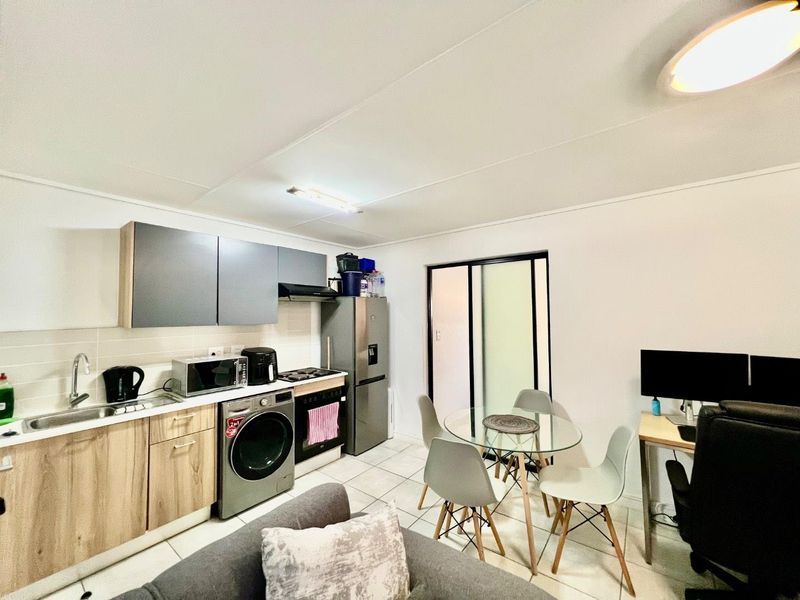 Open-plan living area featuring a modern kitchen with built-in cabinetry, integrated appliances, tiled flooring, and a sliding door leading to the exterior.