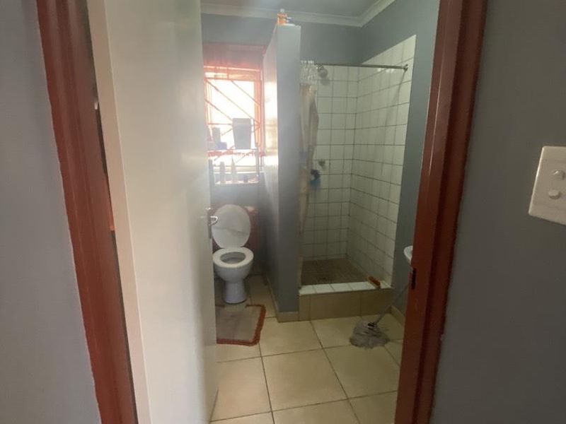 A functional bathroom featuring a shower enclosure, toilet, and tiled finishes, viewed from the doorway.
