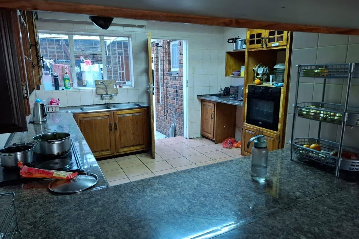 A functional kitchen featuring wooden cabinetry, granite countertops, a built-in oven, and direct access to an exterior courtyard area.