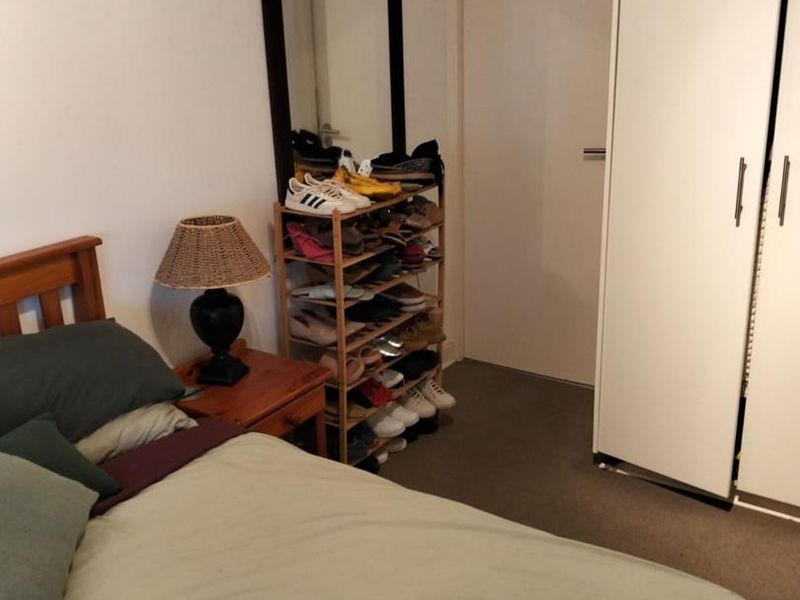 A bedroom featuring neutral walls, carpet flooring, and a built-in wardrobe providing storage space.