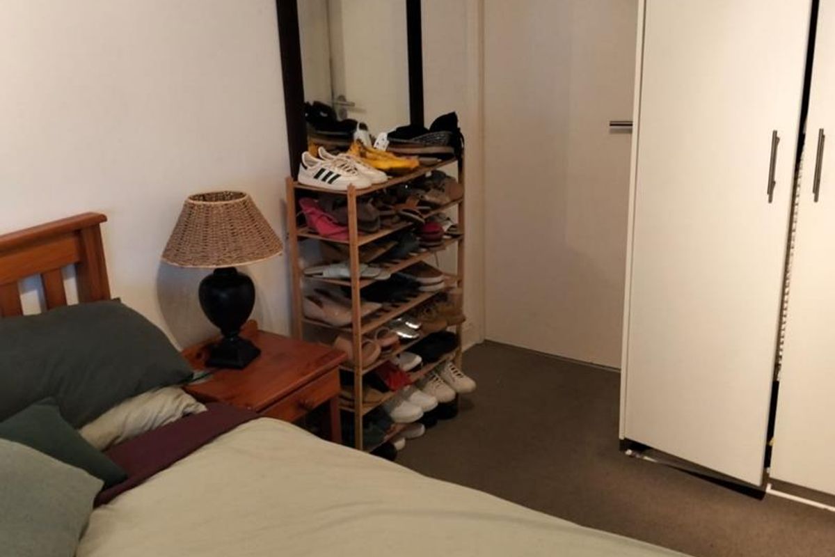 A bedroom featuring neutral walls, carpet flooring, and a built-in wardrobe providing storage space.