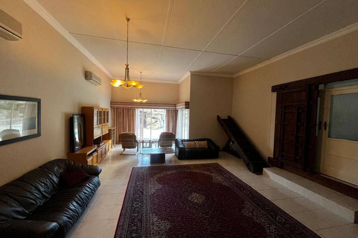 Spacious living room featuring tiled flooring, split-system air conditioning, and large windows with access to the outdoor area.