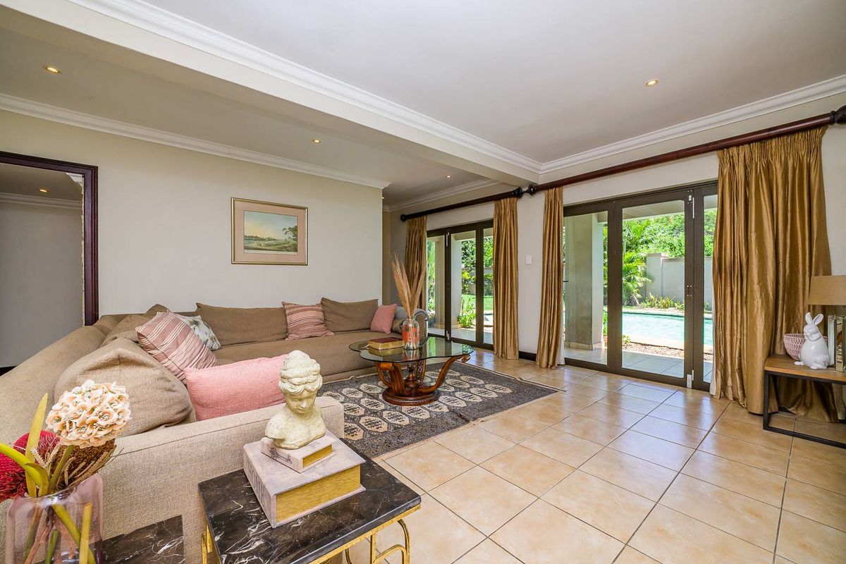 Spacious living area featuring tiled flooring, recessed ceiling lighting, and large sliding glass doors providing direct access to the outdoor patio and pool area.