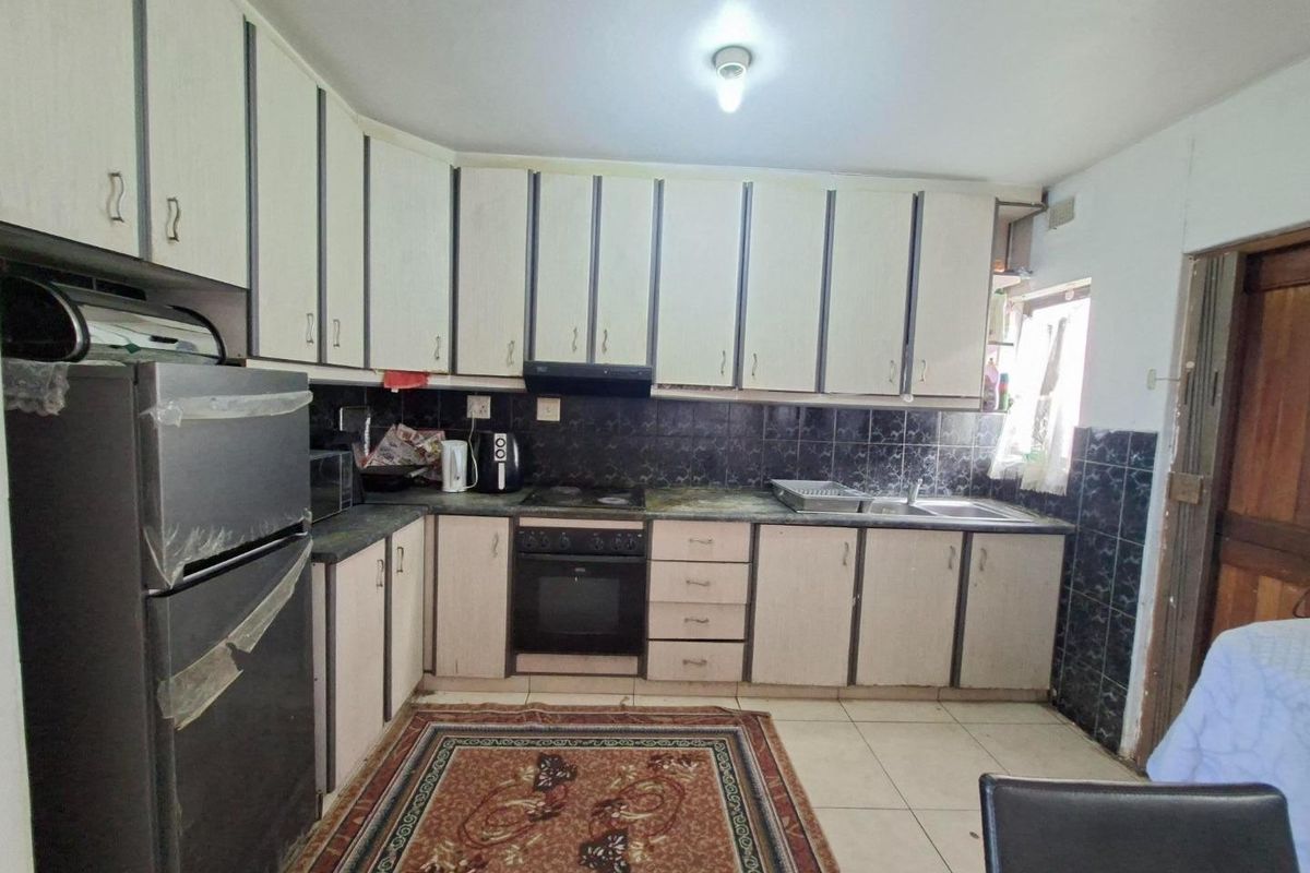 A functional kitchen featuring built-in cabinetry, a hob, an oven, and a tiled backsplash, offering a dated aesthetic ready for modernization.