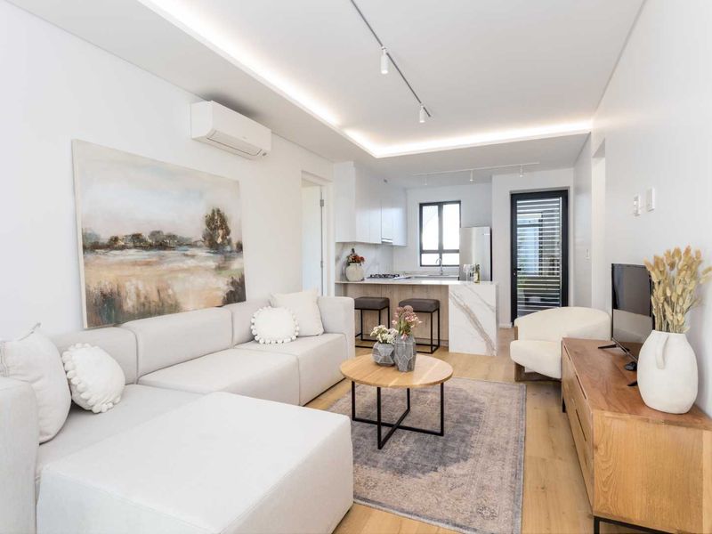 Modern open-plan living area featuring a sleek kitchen with marble-look island, recessed lighting, and timber-look flooring, creating a bright and contemporary atmosphere.