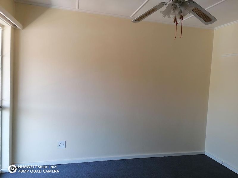 An empty bedroom featuring neutral walls, carpet flooring, and a ceiling fan, providing a blank canvas for personalization.