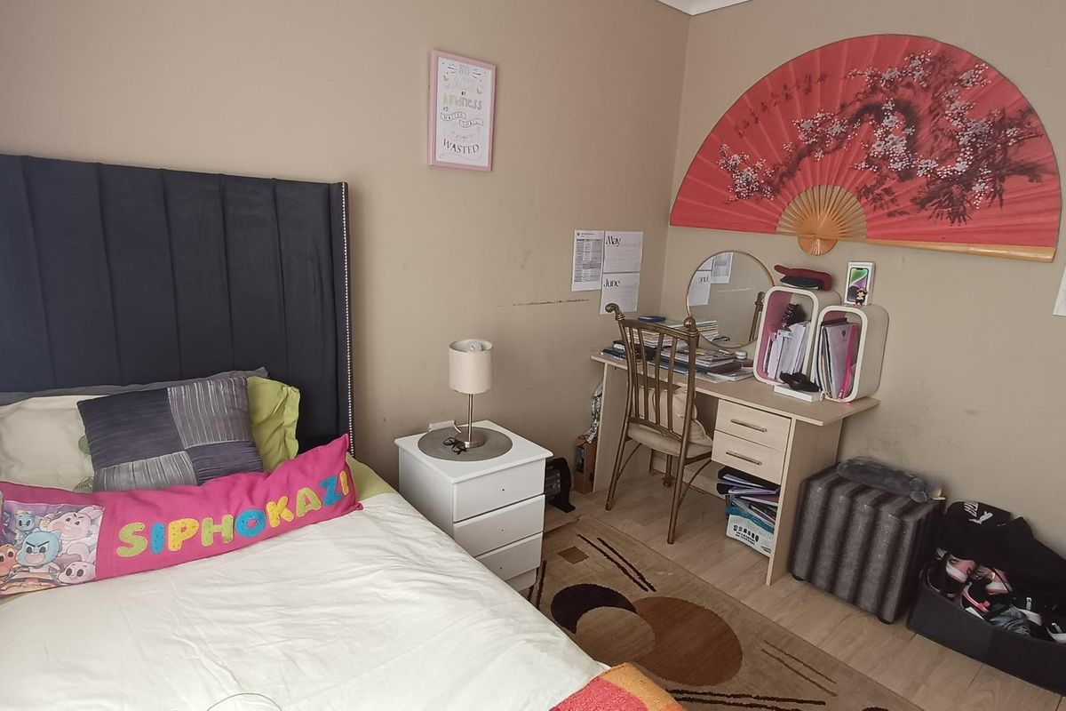 A bedroom featuring light-toned laminate flooring and neutral wall finishes, providing a functional space for rest and study.