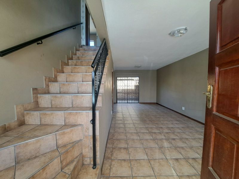 Entrance area featuring tiled flooring, a staircase with a wrought iron balustrade, and a secure rear exit door.