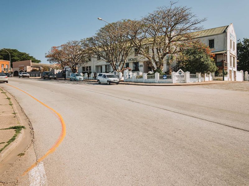Street view of the Heritage Guest House property, showcasing the building facade, perimeter wall, and surrounding street infrastructure.