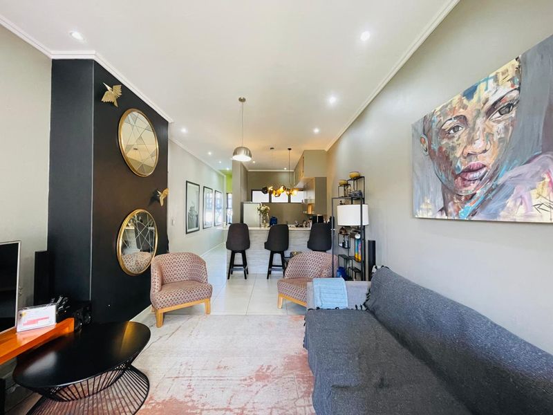 An open-plan living and kitchen area featuring tiled flooring, recessed lighting, and a central kitchen island with breakfast bar seating.