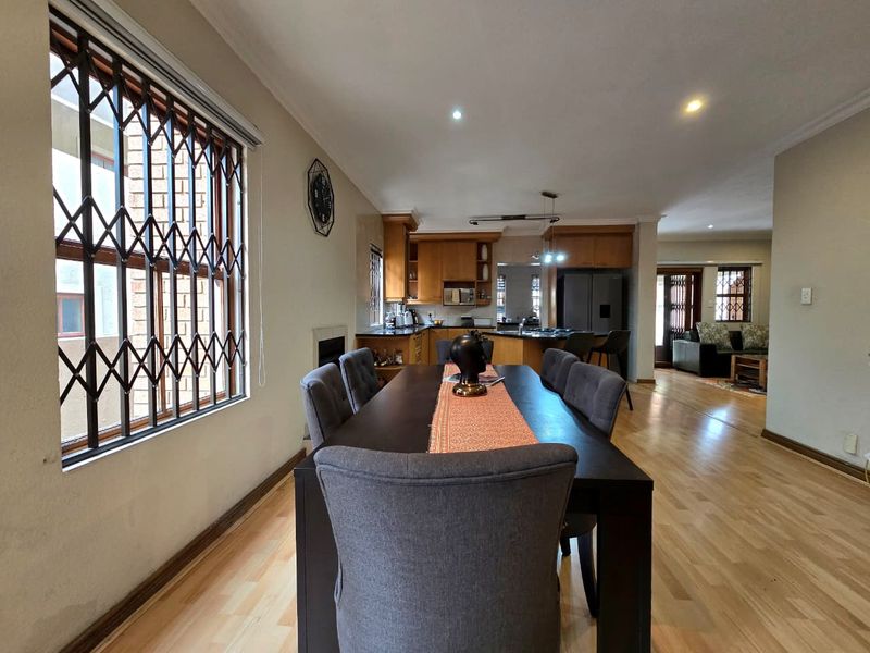 Open-plan living and dining area featuring laminate flooring, recessed lighting, and a functional kitchen with wooden cabinetry and a central island.