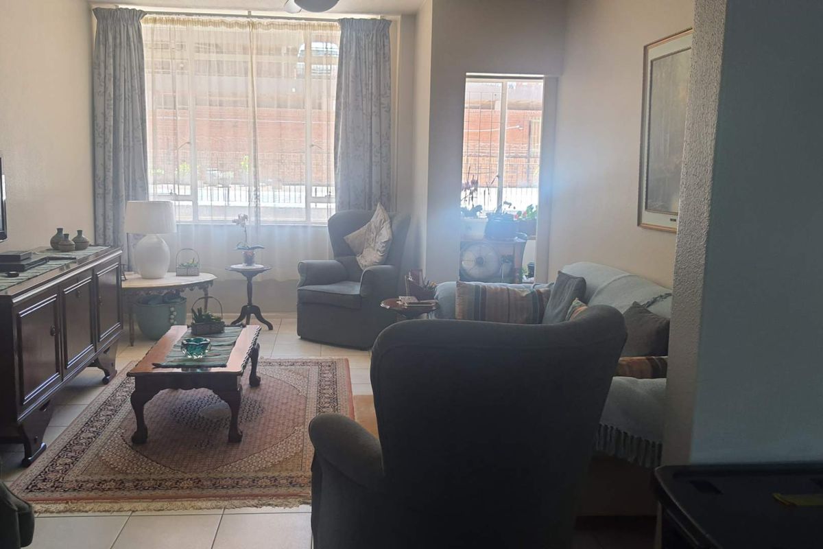 A comfortable living room featuring tiled flooring and large windows that provide natural light, creating a welcoming and functional space.