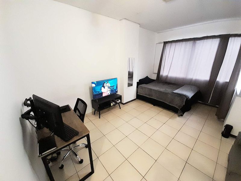 A functional bedroom featuring tiled flooring and a built-in mirror, offering a neutral space ready for personalization.
