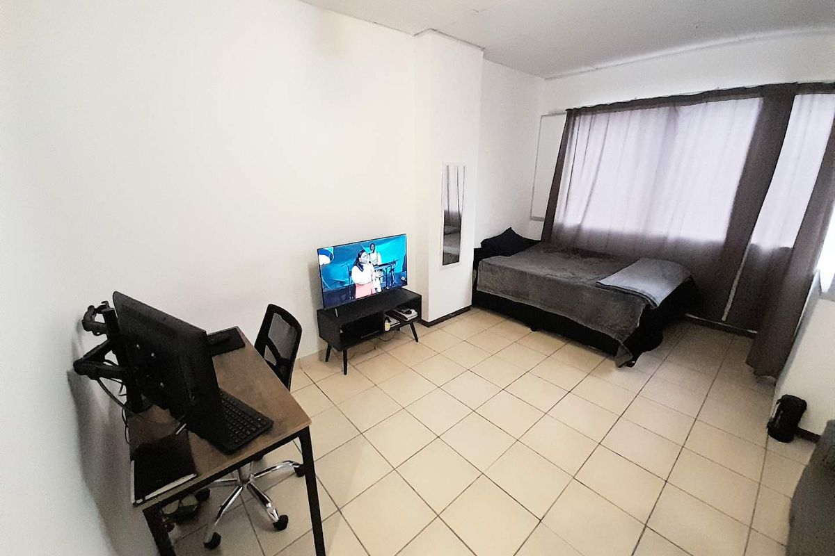 A functional bedroom featuring tiled flooring and a built-in mirror, offering a neutral space ready for personalization.