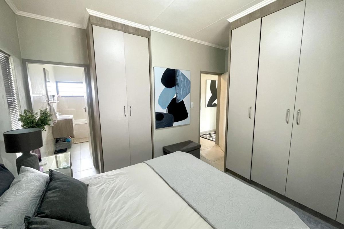 A well-maintained bedroom featuring extensive built-in cabinetry and an en-suite bathroom, offering clean lines and neutral finishes.