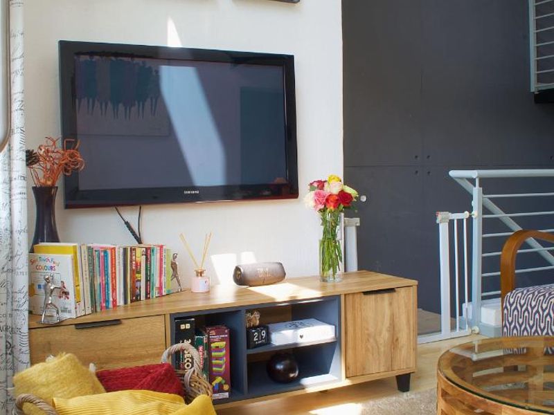 A bright living room featuring laminate flooring, a modern accent wall, and an open staircase with a metal railing.