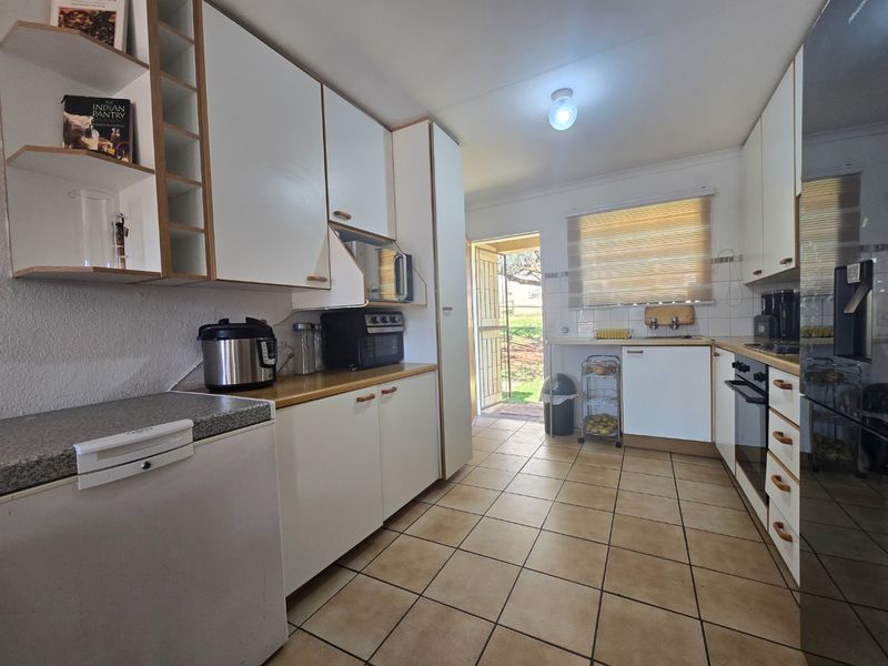 Functional kitchen featuring white built-in cabinetry, laminate countertops, tiled flooring, and direct access to the rear exterior.