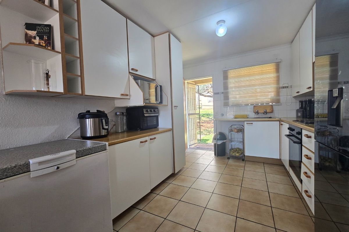 Functional kitchen featuring white built-in cabinetry, laminate countertops, tiled flooring, and direct access to the rear exterior.