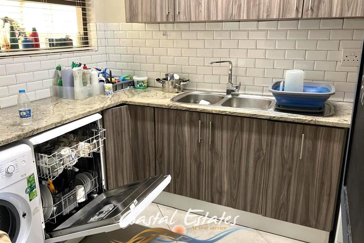 A functional kitchen featuring wood-grain cabinetry, granite countertops, a double-basin sink, and a subway tile backsplash.