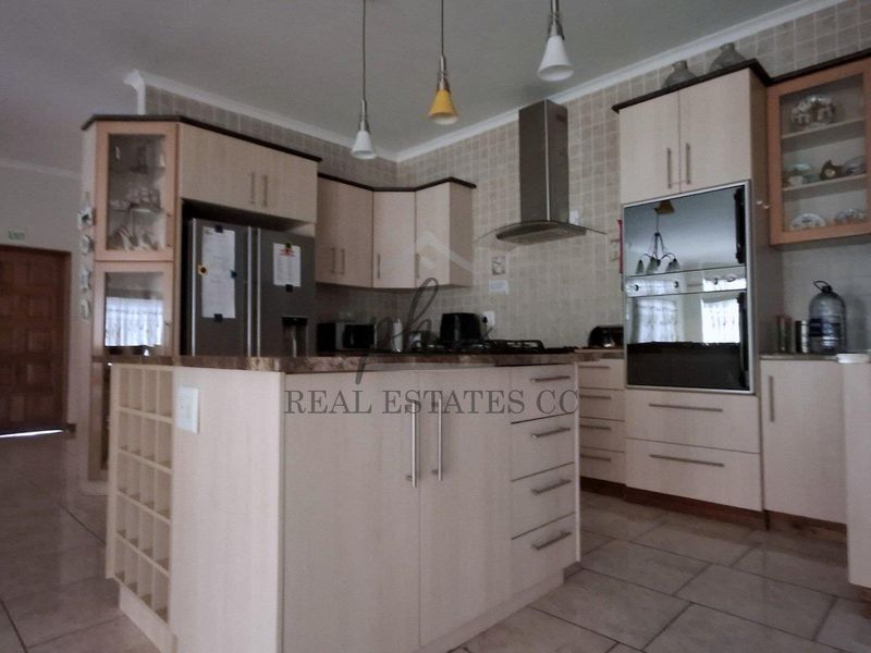 A functional kitchen featuring light-toned cabinetry, a central island, built-in oven, extractor fan, and tiled finishes throughout.