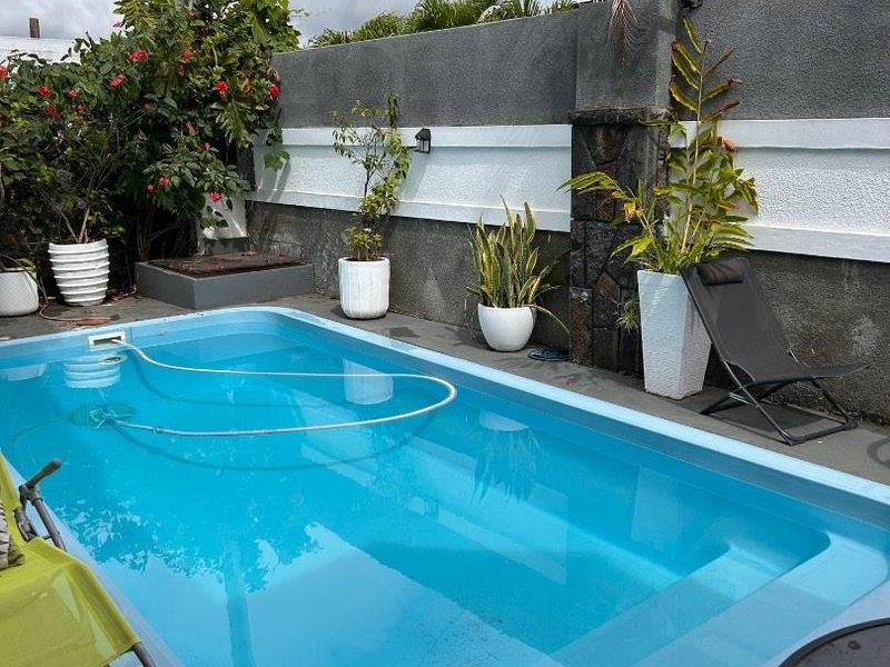 A private outdoor pool area featuring a compact swimming pool, paved surround, and a decorative boundary wall with integrated lighting.