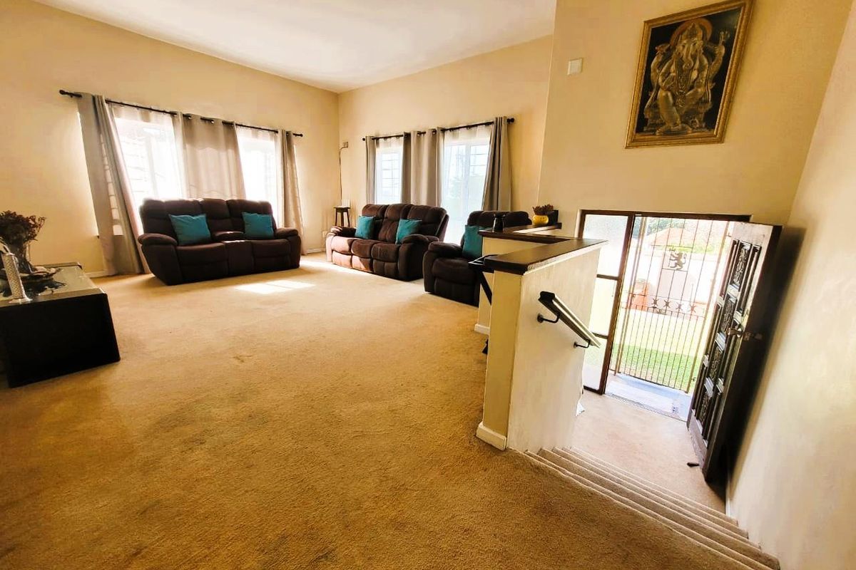 Spacious living area featuring large windows, neutral wall finishes, and a staircase leading to the main entrance.