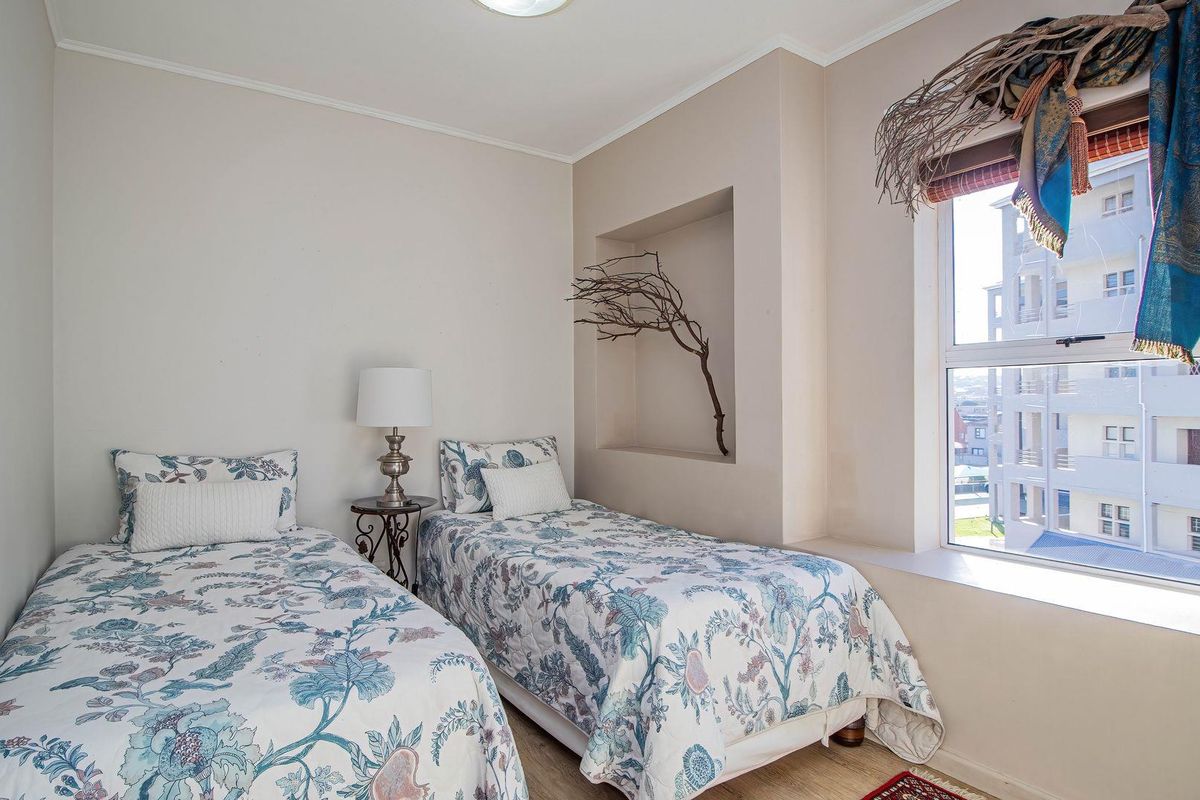 A well-maintained bedroom featuring a built-in wall niche, large window with natural light, and neutral wall finishes.