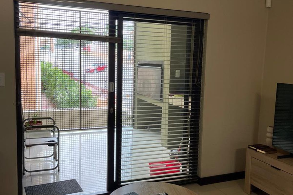 Living room featuring large sliding glass doors that open onto a covered patio area with a built-in braai.
