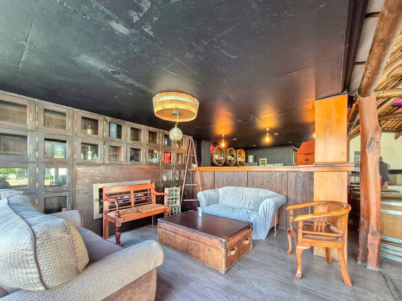A rustic-style bar area featuring extensive timber wall paneling, built-in display cabinetry, and a dedicated bar counter with integrated shelving.