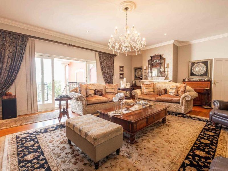 Elegant living room featuring hardwood flooring, crown molding, a crystal chandelier, and sliding glass doors leading to an outdoor area.