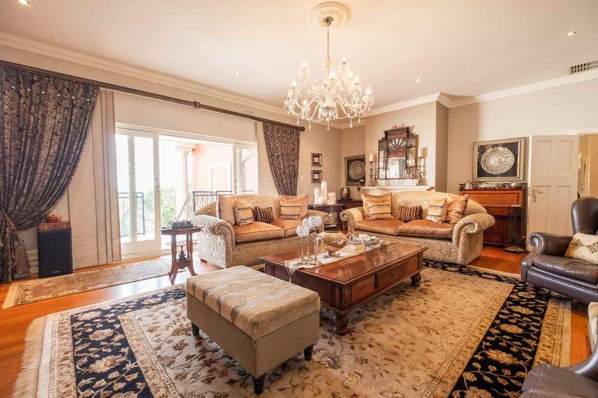 Elegant living room featuring hardwood flooring, crown molding, a crystal chandelier, and sliding glass doors leading to an outdoor area.