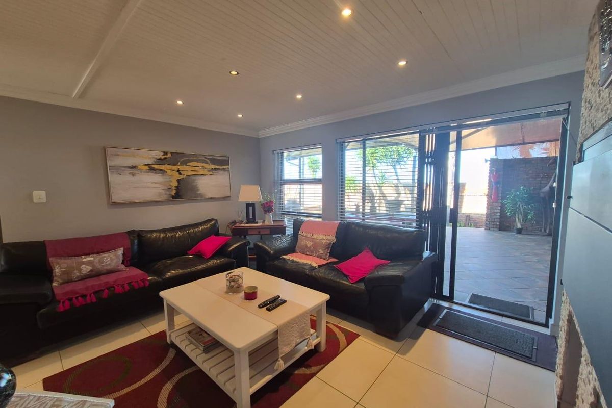 Spacious living room featuring tiled flooring, recessed ceiling lighting, and large sliding glass doors providing seamless access to the outdoor patio area.