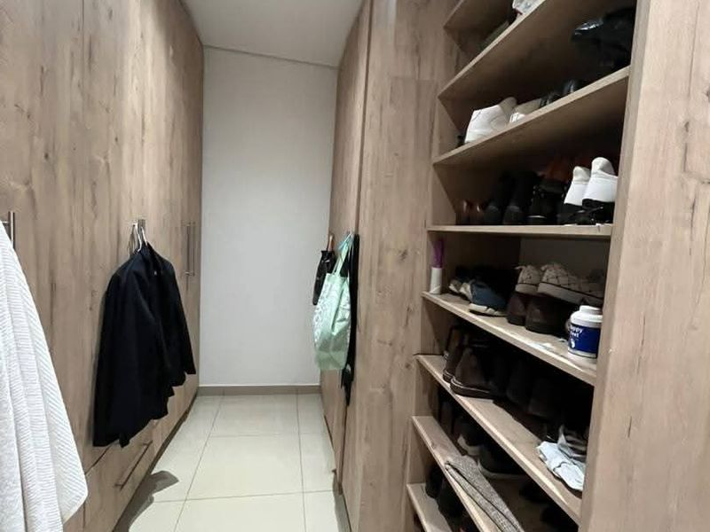 A walk-in closet featuring extensive floor-to-ceiling wood-finish built-in cabinetry and open shelving for organized storage.
