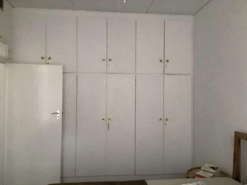 A bedroom featuring floor-to-ceiling built-in cupboards with white cabinetry, providing ample storage space.