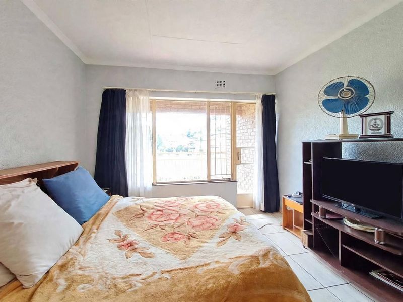 A bedroom featuring tiled flooring and a sliding door with a security gate, providing access to an outdoor area.