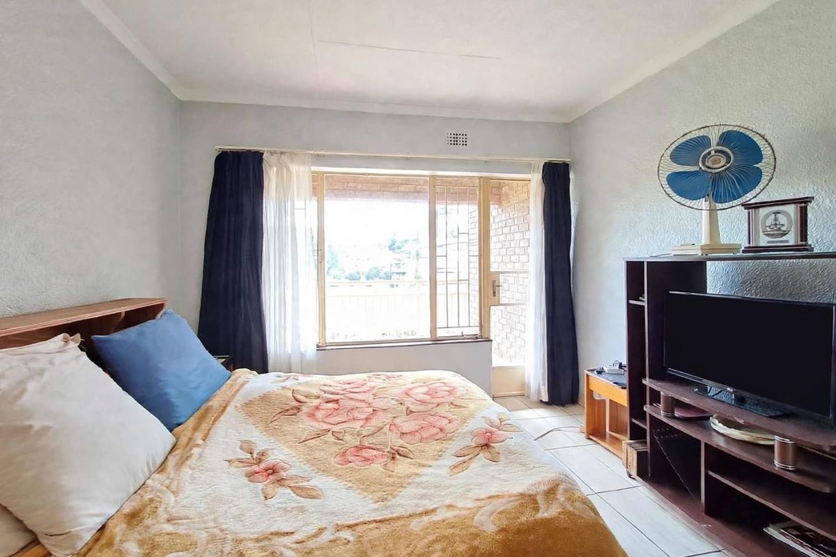 A bedroom featuring tiled flooring and a sliding door with a security gate, providing access to an outdoor area.