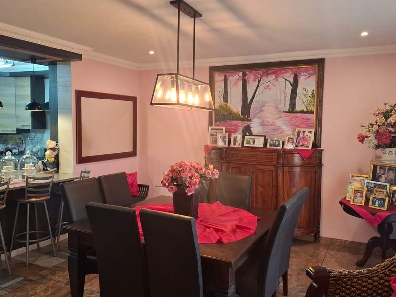 Open plan dining and kitchen area featuring granite countertops, modern pendant lighting, and tiled flooring, creating a functional and connected living space.