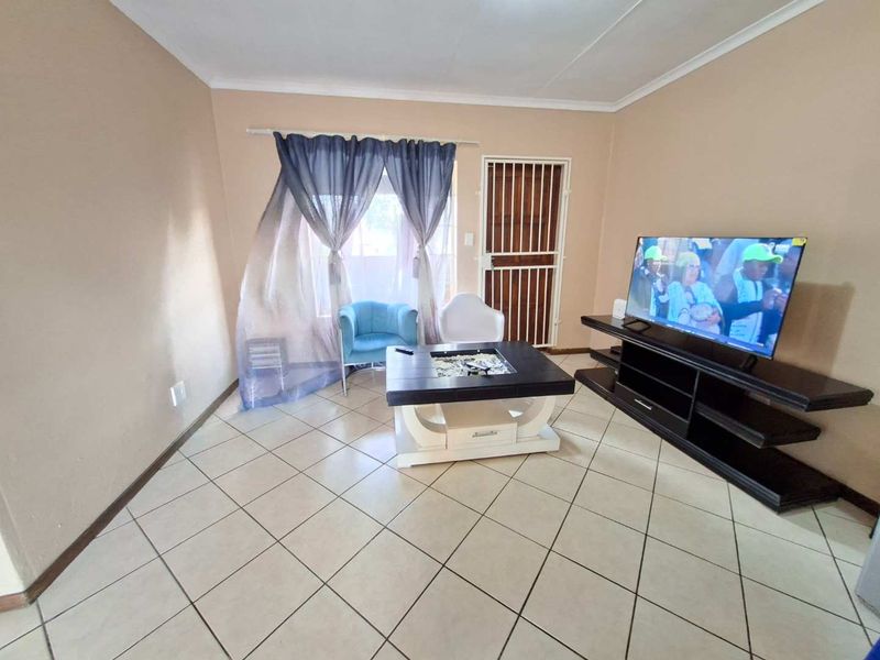 A living room featuring tiled flooring and a security gate, providing a functional and accessible space for relaxation.