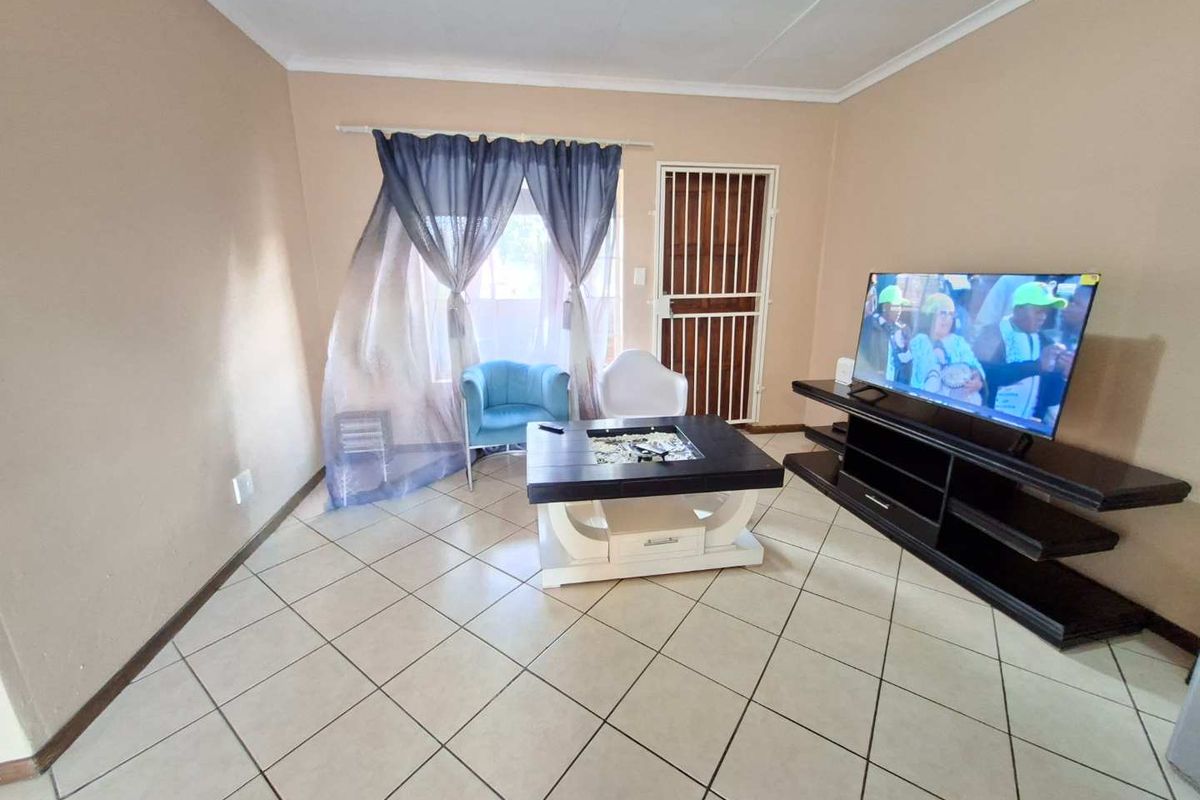 A living room featuring tiled flooring and a security gate, providing a functional and accessible space for relaxation.
