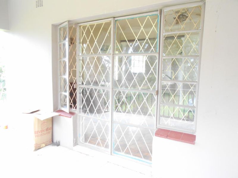 A covered patio area featuring steel security gates and window frames, providing access to the exterior space.