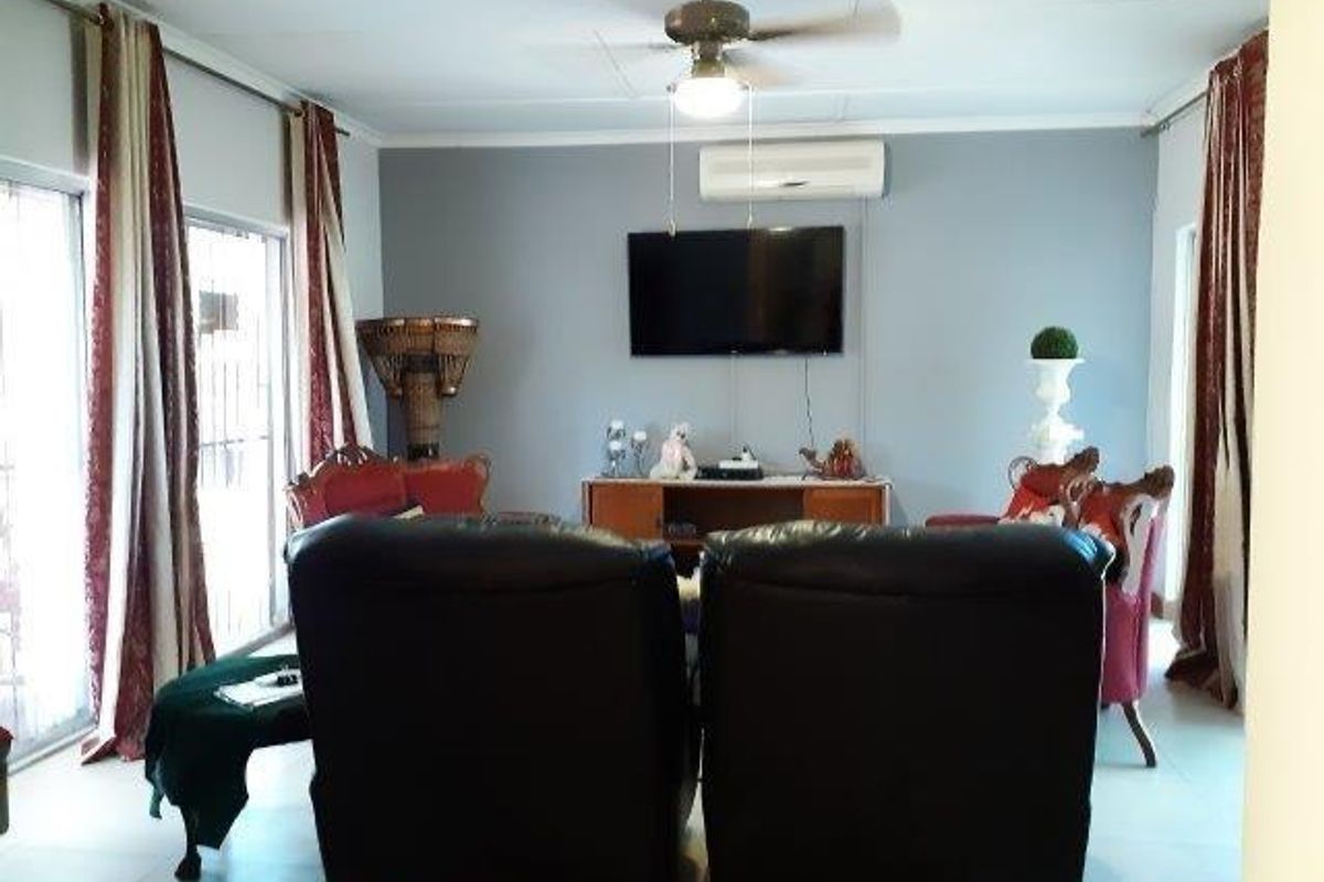 A comfortable living room featuring a ceiling fan, wall-mounted air conditioning unit, and large sliding glass doors providing natural light.