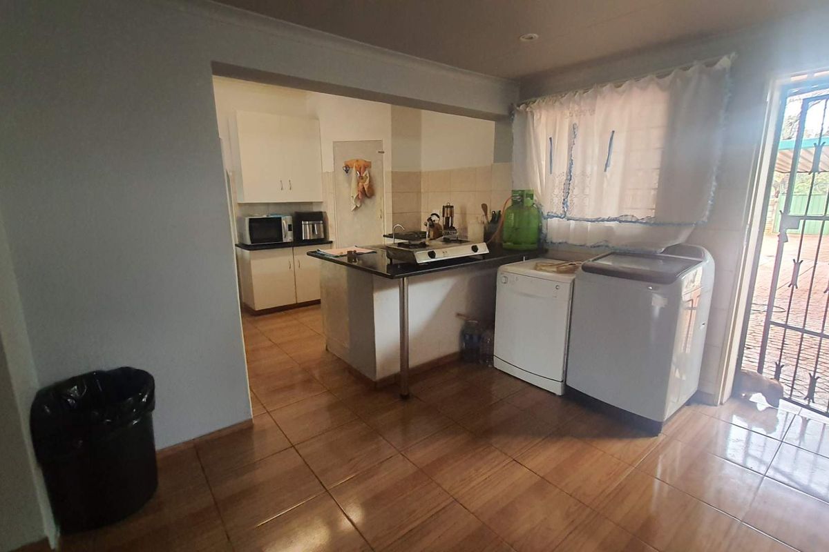 A functional kitchen and laundry area featuring tiled flooring, built-in cabinetry, and direct access to the exterior through a security gate.
