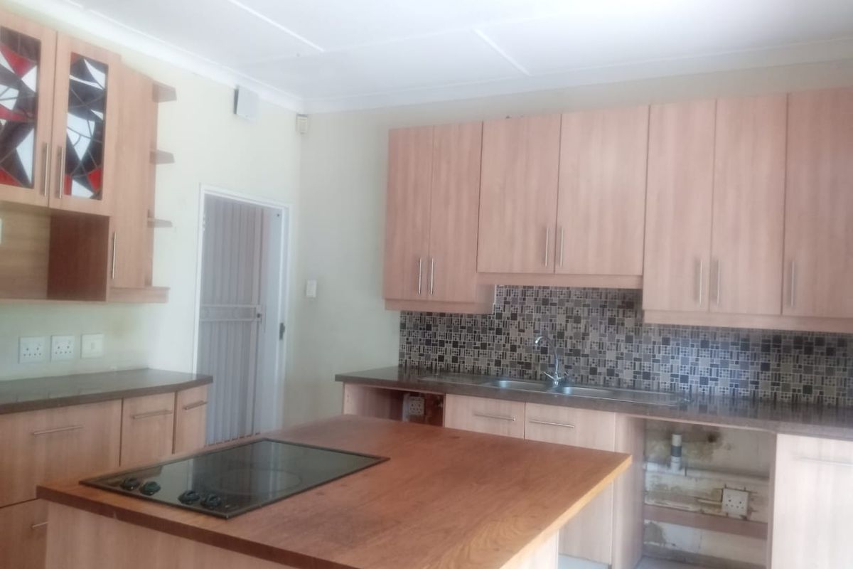 A kitchen featuring light wood cabinetry, a mosaic tile backsplash, and a central island with an integrated hob, requiring minor repairs to cabinetry and finishes.