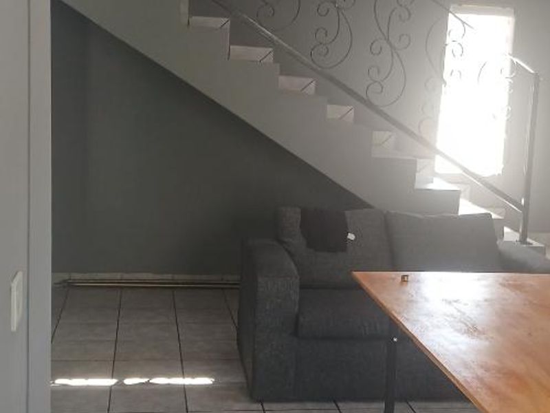 Living area featuring tiled flooring and a staircase with a decorative wrought iron balustrade.